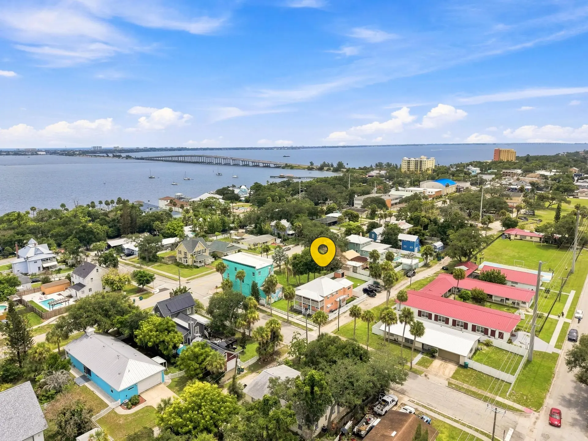 Daytime aerial of the Eau Gallie neighborhood showing the home, palm-lined streets, the Indian River Lagoon and the causeway bridge